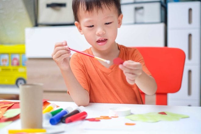 toddler boy enjoy using glue doing arts at home
