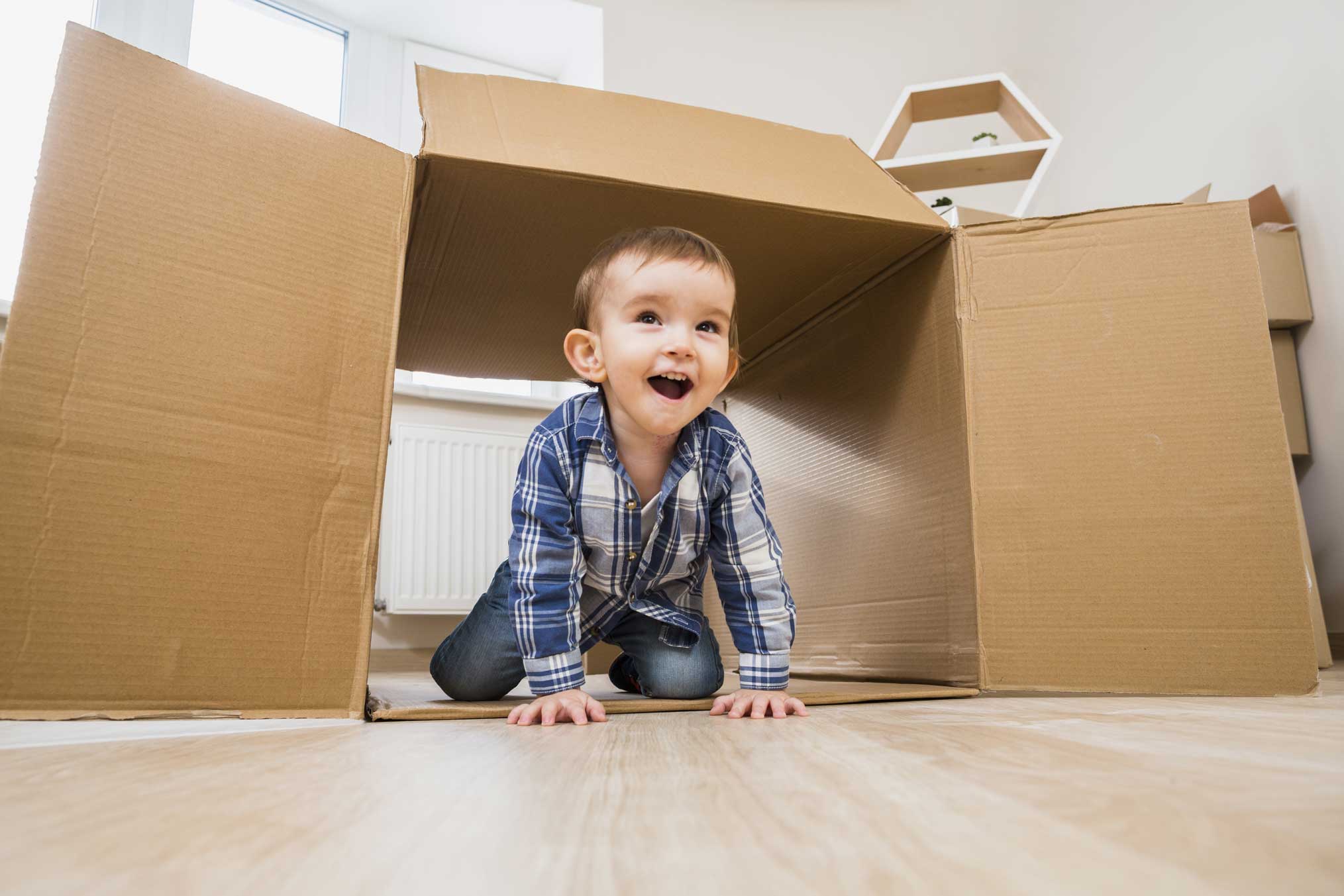 Main happy baby toddler crawling inside open cardboard box home