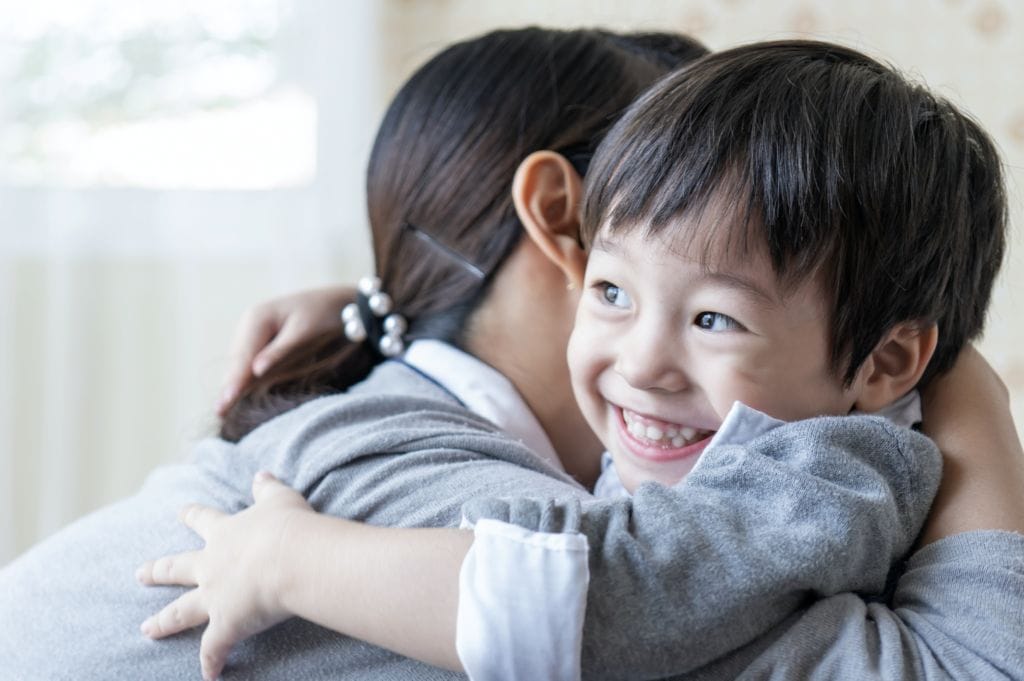 asian cute boy smiling with happily hugging with mother home family concept