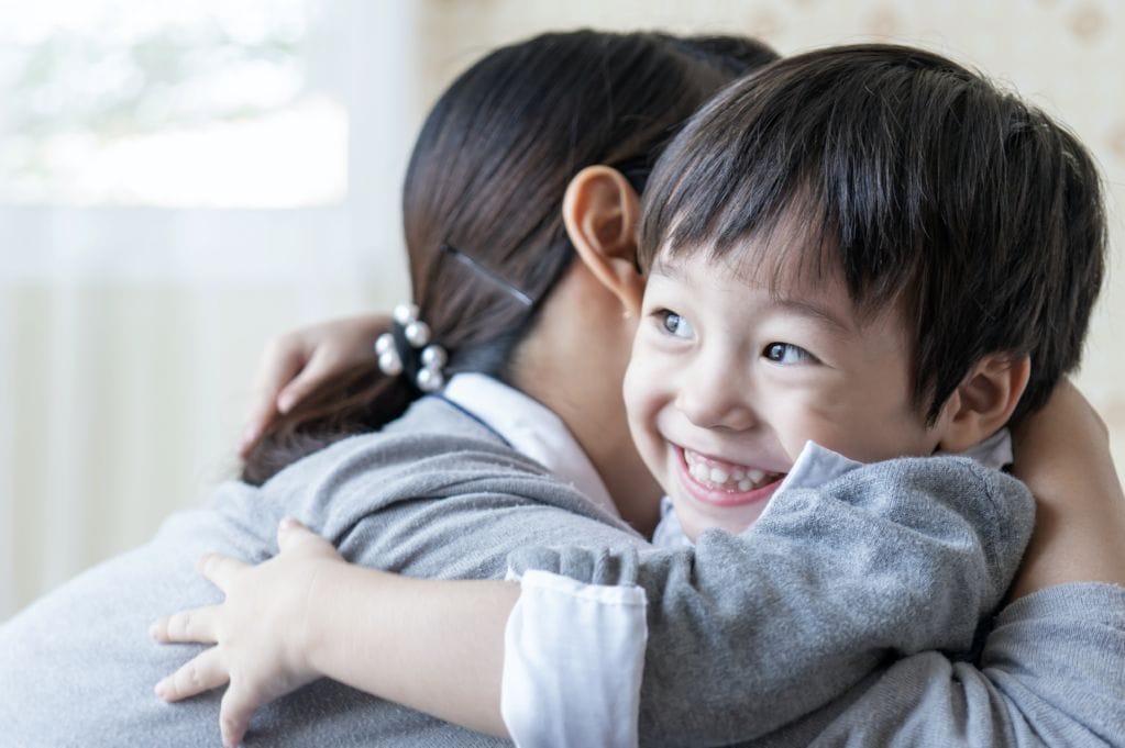 asian cute boy smiling with happily hugging with mother home family concept