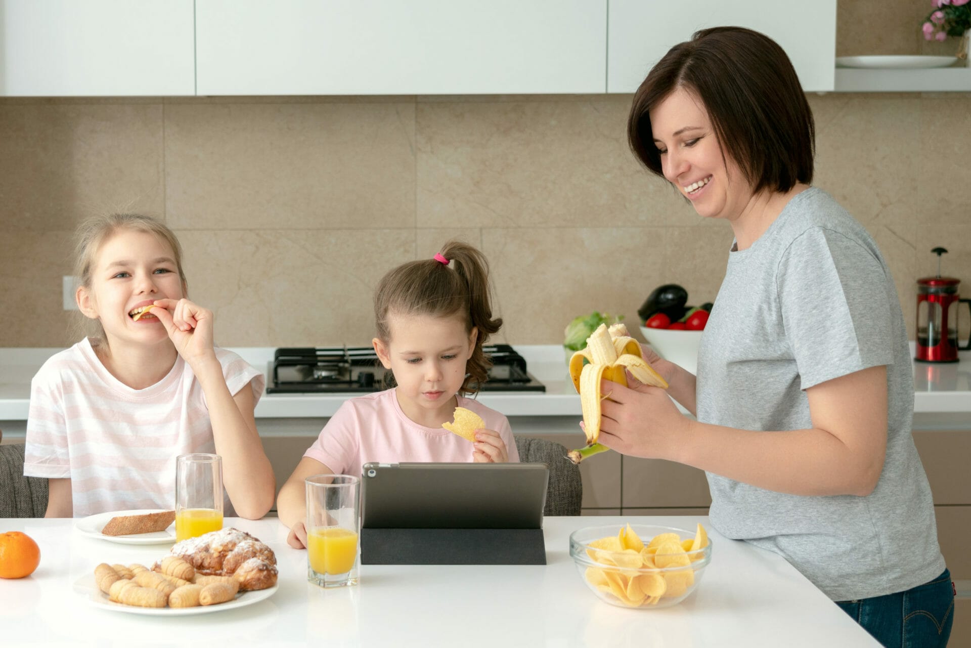 Sisters eating delicious pasta in kitchen