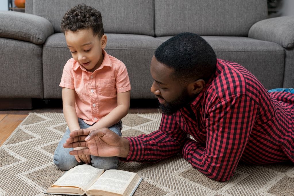 father and cute son reading book on couch
