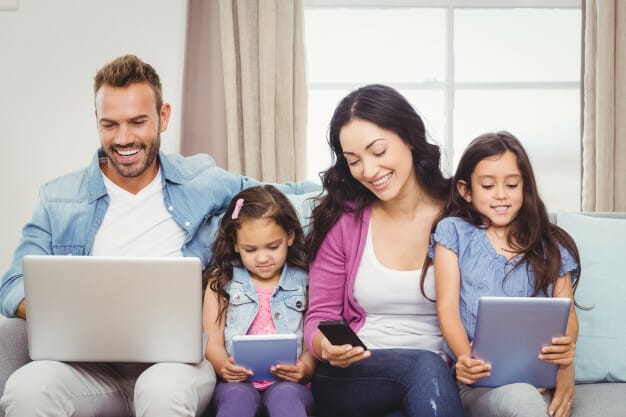 family using modern technologies while sitting sofa