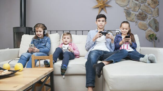 Boys playing video games and girls using smartphones