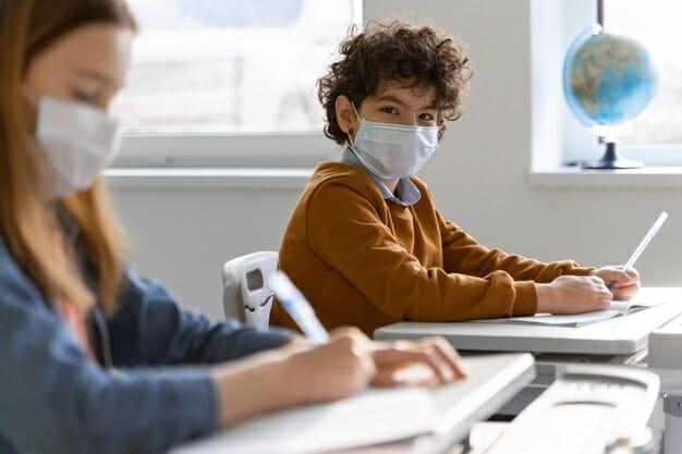 Student with medical mask getting hand sanitizer from teacher
