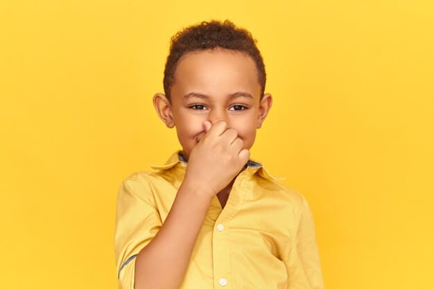 Disgusted displeased dark skinned boy pinching nose with fingers, holding breathe because of unpleasant gross stink