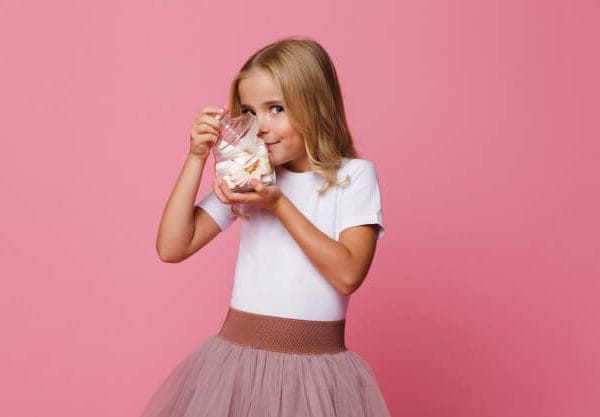 Portrait of an excited little girl holding jar of marshmallow