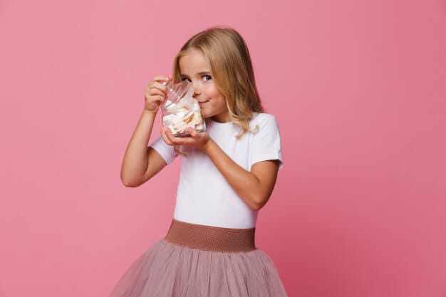 Portrait of an excited little girl holding jar of marshmallow