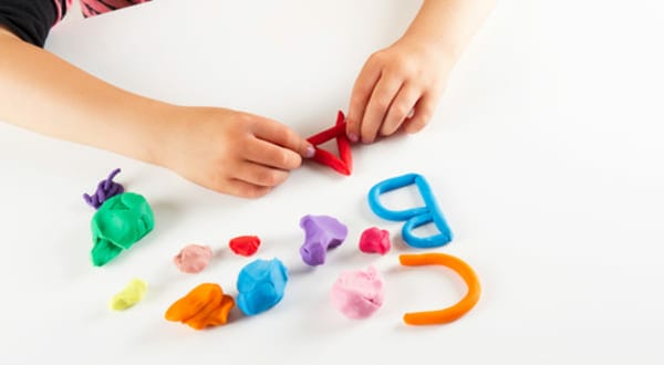 Child hands with colorful clay. Mold letters