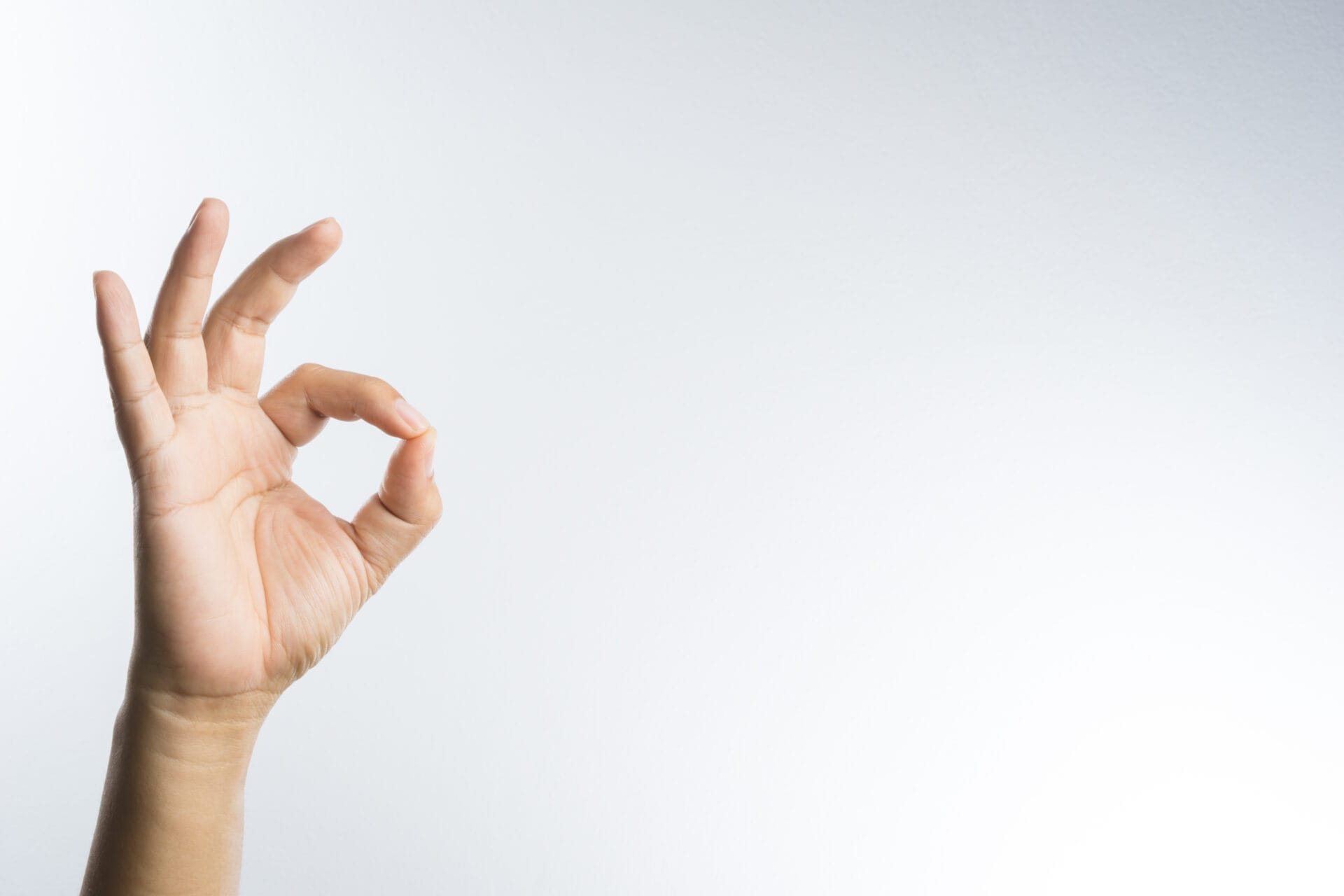 A hand is making an OK sign on a white background